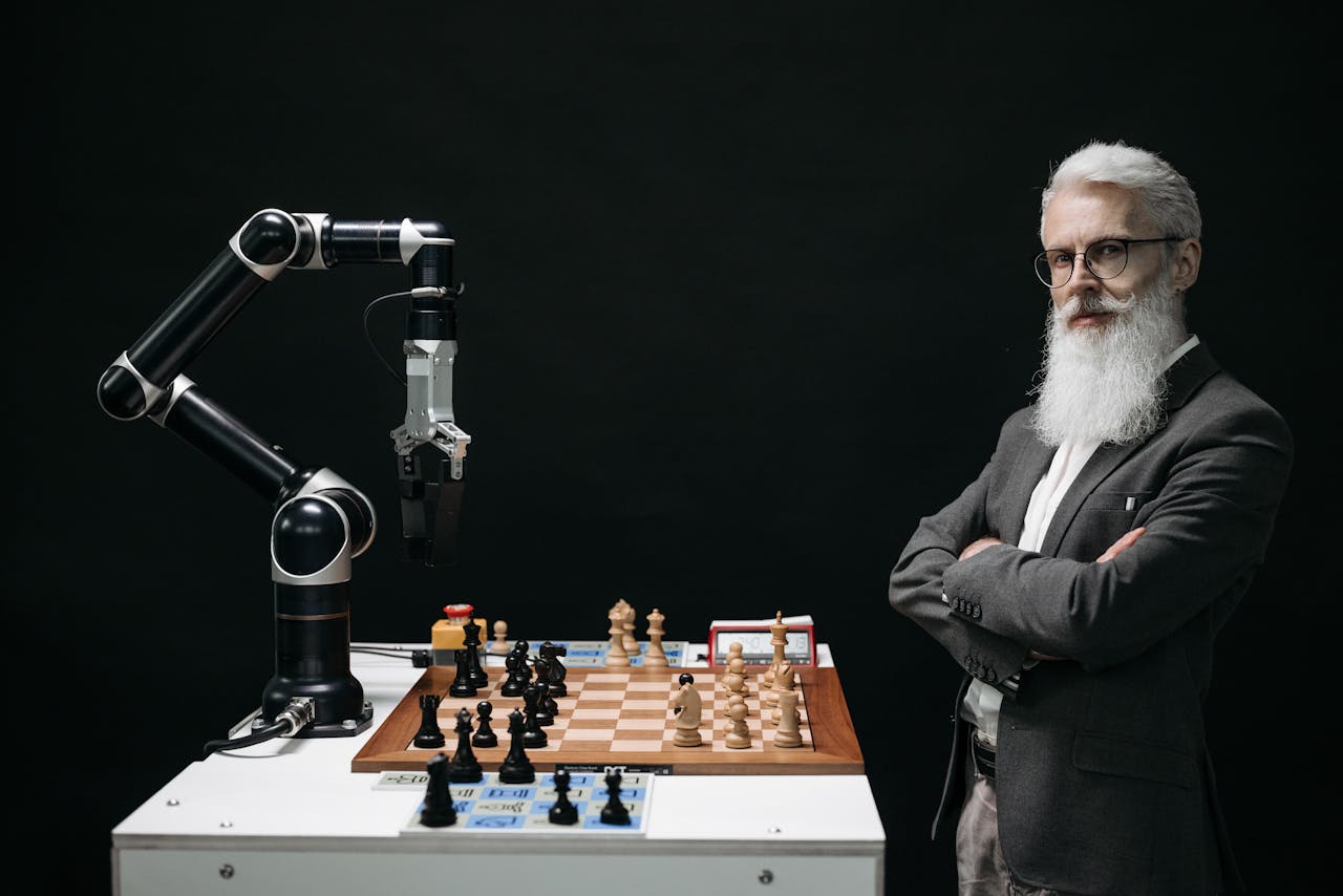 hero-img A robotic arm and a bearded man engaged in a strategic chess game highlighting technology and innovation.